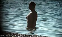 נערת חזה עם גוף טבעי מסתובבת על חוף נודיסטים