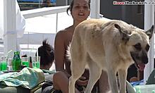Fata amatoare cu sânii mici se joacă cu un câine pe plajă