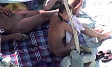 Krásná brunetka v odstínech ukazuje své nahé tělo na nudistické pláži